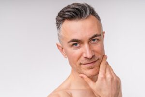 A man staring intensely at the camera and holding his chin