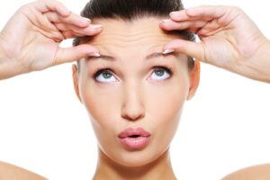 A woman making a surprised expression and pinching the wrinkles on her forehead with her fingers