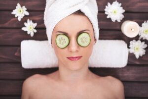 A photo from above of a woman lying down with cucumbers over her eyes in a spa environment
