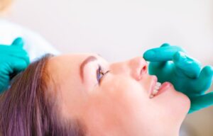 Close-up of a surgeon examining the nose of a smiling patient