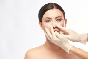 A surgeon checking the nose of a patient. Only the surgeon's hands are visible.